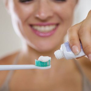 woman putting toothpaste on an electric toothbrush 