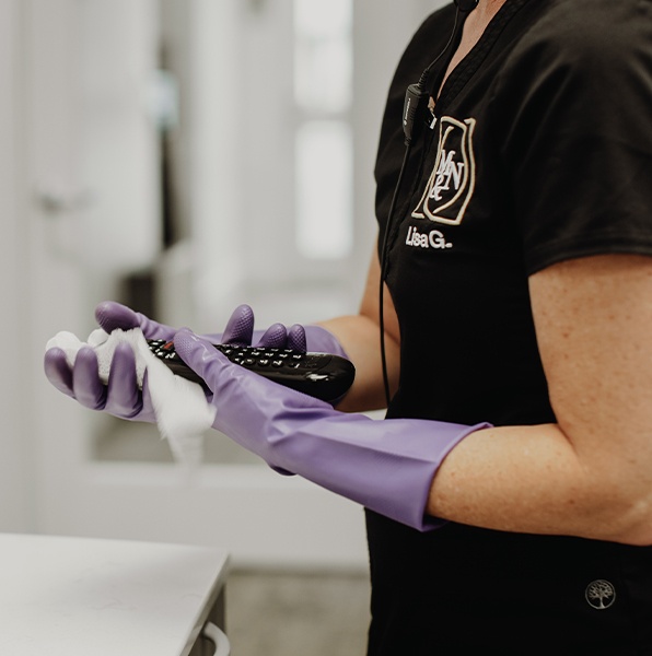 Dental team member sanitizing equipment