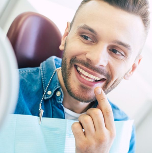 Smiling dental patient holding mirror
