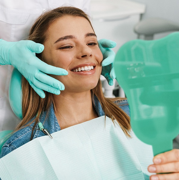 Smiling dental patient holding mirror