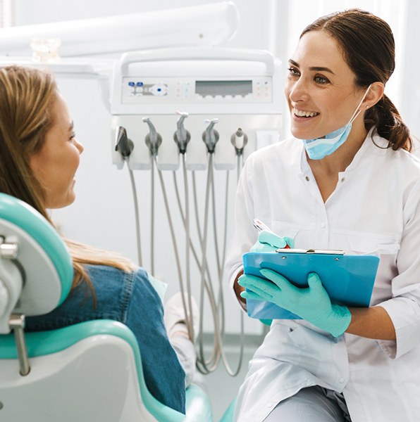 Dentist smiling at patient while taking notes on clipboard