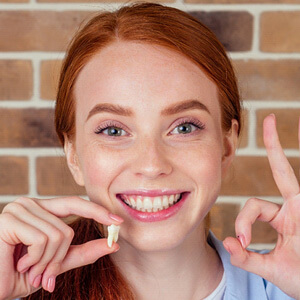 someone holding a tooth and smiling