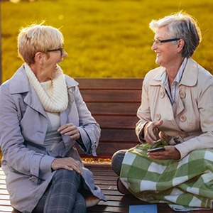 two mature women smiling and conversing together