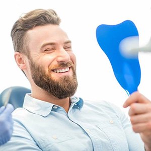 a patient checking his new dentures with a mirror