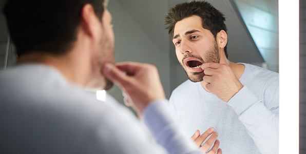 Man with lost filling looking at smile in mirror