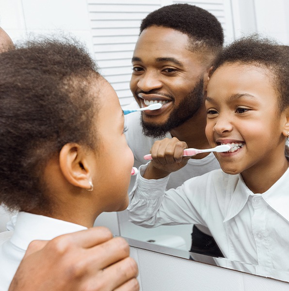 Father and child brushing teeth to prevent dental emergencies