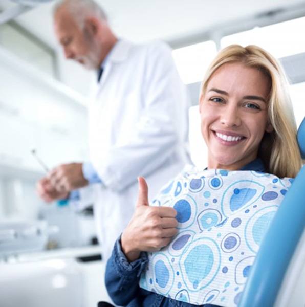 woman with dental implants in Jacksonville giving thumbs up in dental chair  