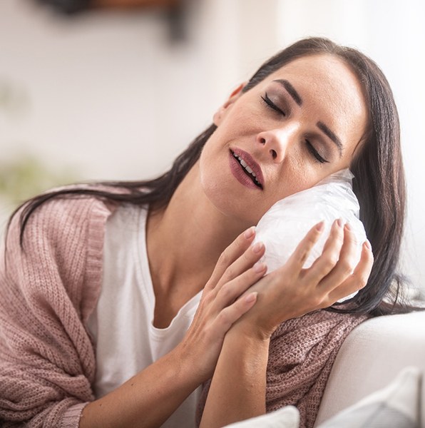 a woman placing an ice pack on her face 