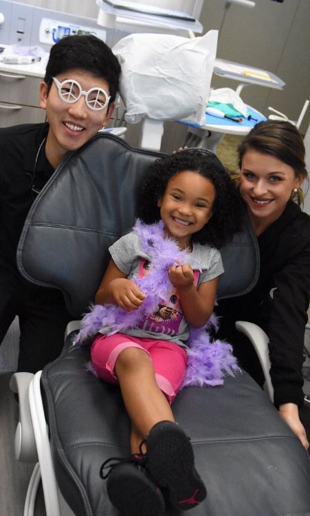 Jacksonville dentist and dental team member smiling with young girl in dental chair