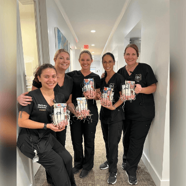 Dental team members holding gift baskets in Jacksonville dental office
