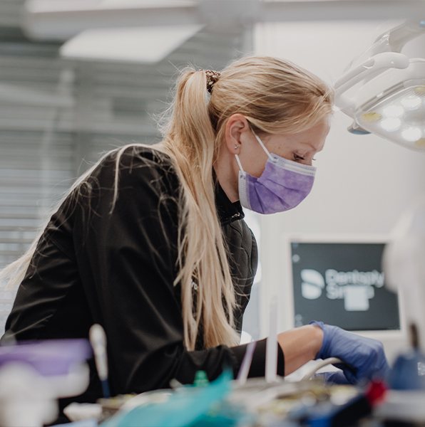 Dental team member examining patient's smile after dental crown restoration