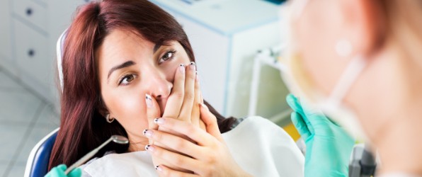 Fearful patient in need of sedation dentistry covering her mouth