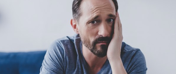 Man in need of emergency dentistry holding his cheek