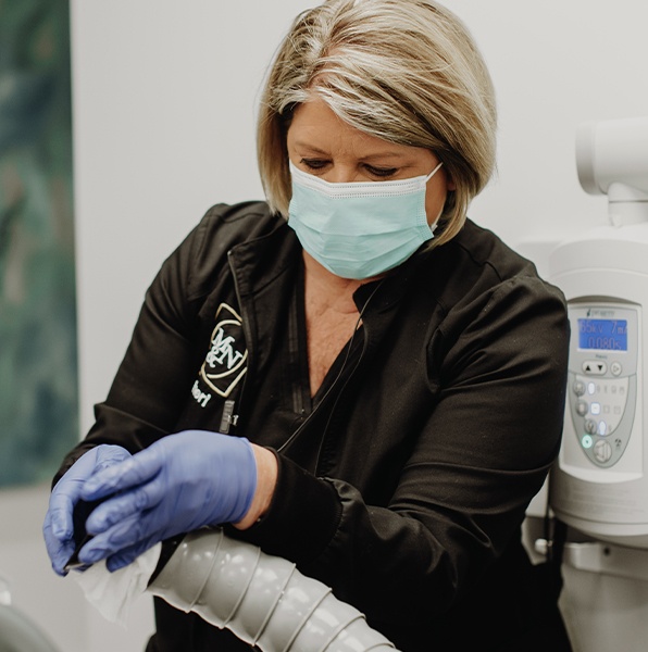 Dental team member using extraoral suction aerosol control system