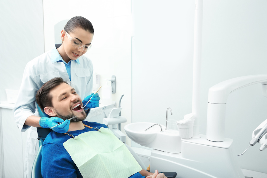 female dentist performing work on male patient