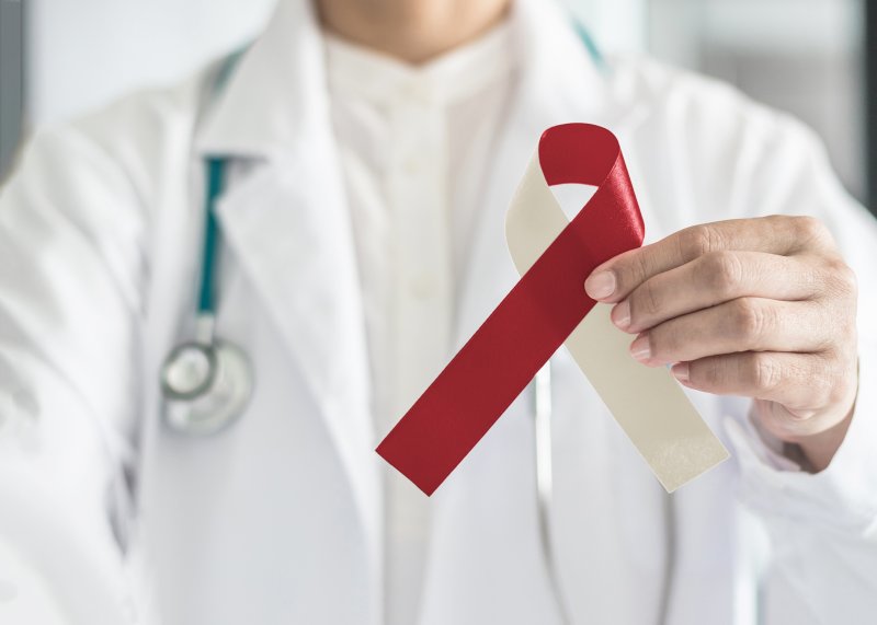 A doctor holding a ribbon that symbolizes Oral Cancer Awareness Month