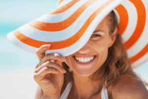 Woman in sunhat smiling brightly while at the beach